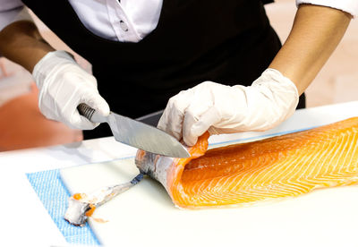 Midsection of chef cutting fish in commercial kitchen