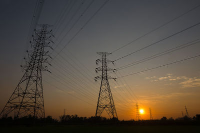 Low angle view of silhouette electricity pylon against sky during sunset