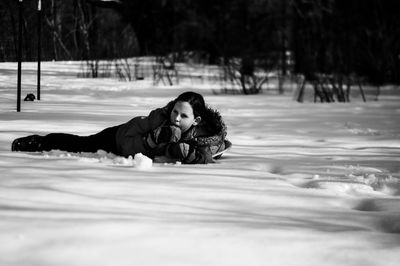 Side view of girl lying on snow covered field