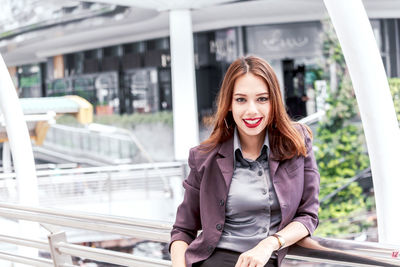 Portrait of smiling young businesswoman standing on elevated walkway 