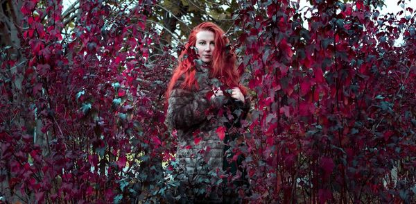 Portrait of a young woman standing by plants