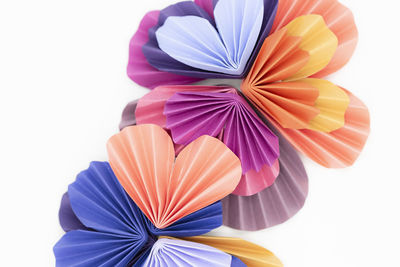Colorful paper hearts folded and arranged into flower shapes on white