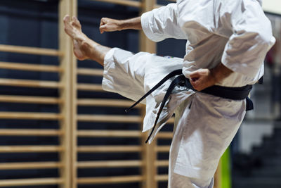 Mature man kicking while practicing karate in class