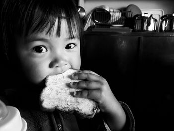 Portrait of cute girl eating bread at home