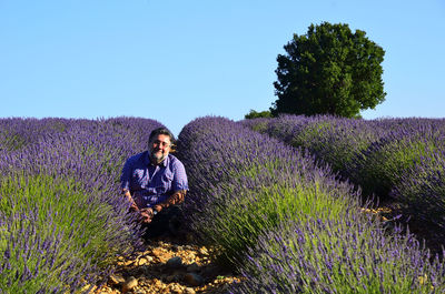 Portrait of woman with purple flowers on field against sky