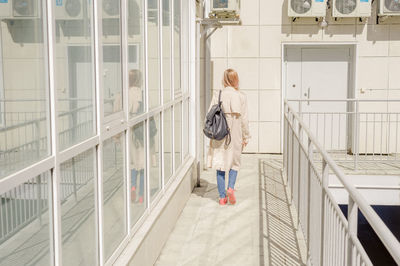 Rear view of young woman with backpack walking in corridor