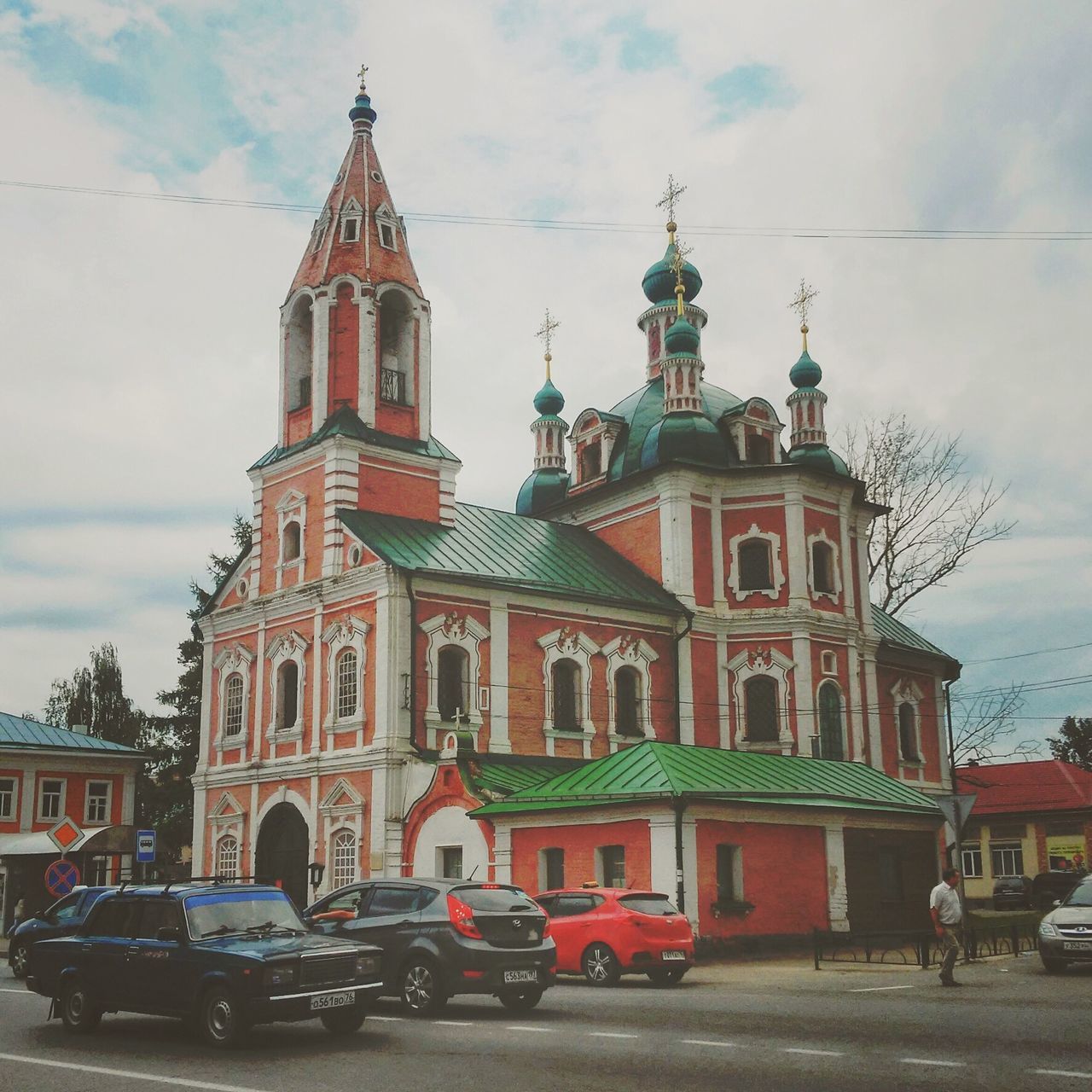 building exterior, architecture, built structure, church, religion, sky, place of worship, transportation, mode of transport, land vehicle, spirituality, car, cloud - sky, street, low angle view, cathedral, travel, incidental people