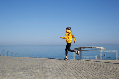 Full length of man standing on railing against sea