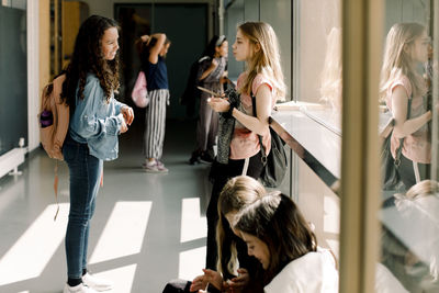 Female students communicating in school corridor during lunch break