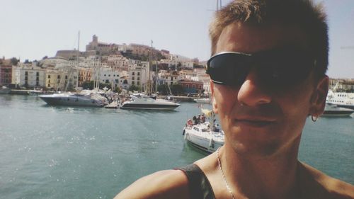 Close-up of man wearing sunglass by lake against sky