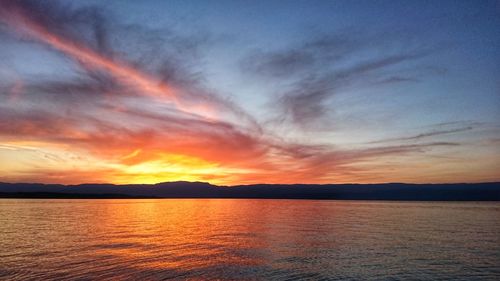 Scenic view of sea against dramatic sky during sunset