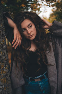 Portrait of woman standing by tree