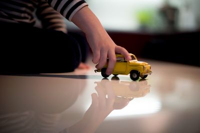 Cropped image of boy playing with toy car at home