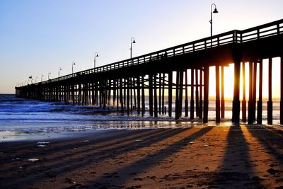 Pier over sea against clear sky during sunset