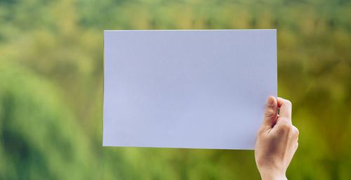 Cropped image of woman holding paper against blurred background