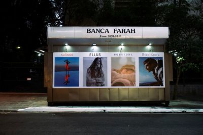 Rear view of people sitting in illuminated building at night