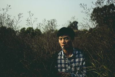 Man smoking while sitting amidst plants