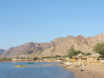 Scenic view of sea and mountains against clear blue sky