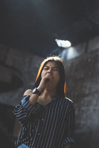 Young woman yawning while standing in abandoned building
