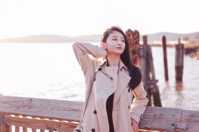 Portrait of beautiful young woman standing in sea against sky