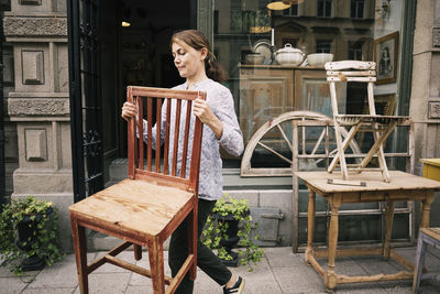 Woman holding chair and walking outside store