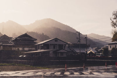 Houses by road against sky in city