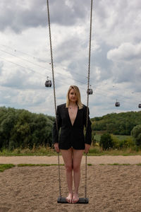 Portrait of young woman on swing in playground