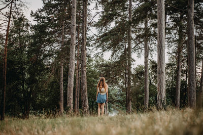 Full length of young woman standing in forest