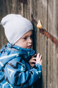 A child peeks through a wooden fence. curious, inquisitive boy explores