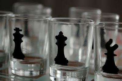 Close-up of chess piece shapes on empty shot glasses at table