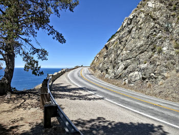 Road by mountains against clear blue sky