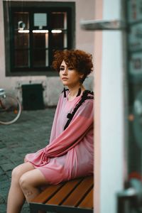 Young woman looking away while sitting outdoors