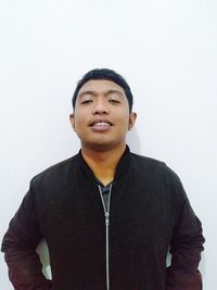 Portrait of young man standing against white background