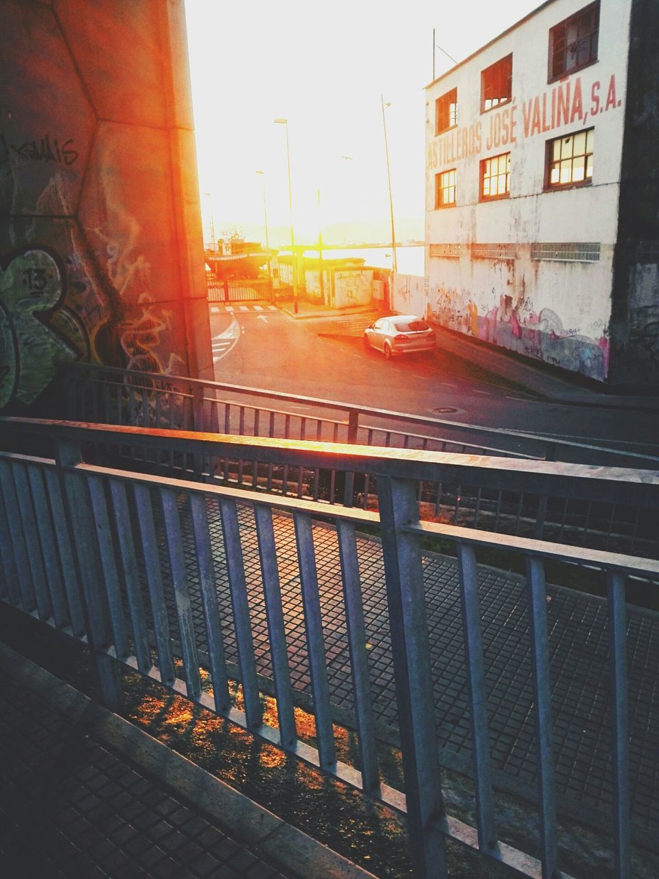 architecture, built structure, building exterior, city, railing, sunset, building, window, sunlight, text, residential building, residential structure, outdoors, sky, no people, balcony, street, day, wall - building feature, western script