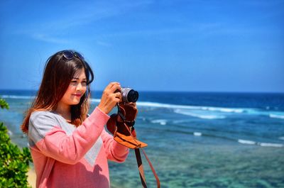 Woman photographing sea from camera