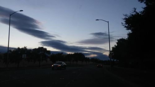 Cars on road against cloudy sky