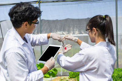 Man and woman using phone while standing on laptop