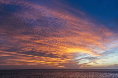 Scenic view of sea against dramatic sky during sunset