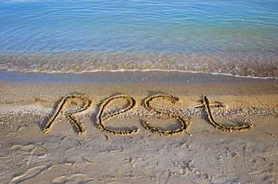 High angle view of rest text on sand at beach