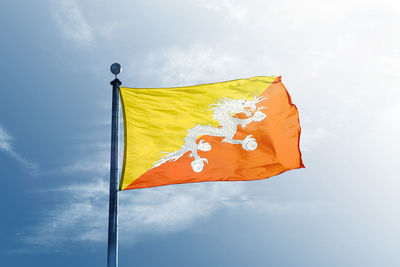 Low angle view of yellow flag against sky