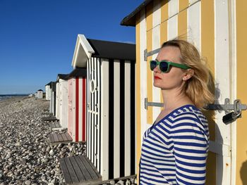 Side view of young woman, who staying at the stripes beach house and looking forward.  