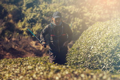 Man standing amidst plants on field