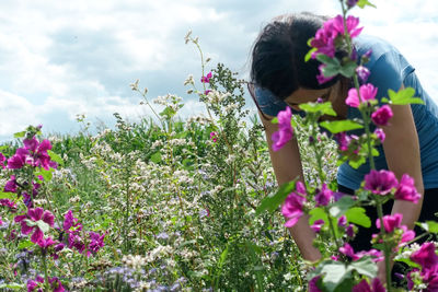 Rear view of woman with pink flowers against sky