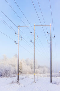 Low angle view of electricity pylons against clear sky