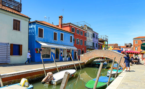 Tourists among the sovereign shops and restaurants on the main street of burano island.