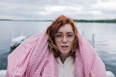 Portrait of beautiful young woman standing against lake