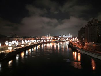 Illuminated bridge over river against sky at night