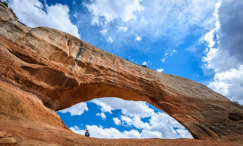 Low angle view of woman on rock formation against sky