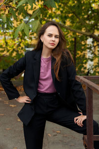 Young woman in black trouser suit and pink t-shirt on the background of the park