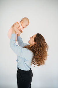 Young mother with long hair and in a shirt holds a newborn daughter. in the arms of a 6 month old 